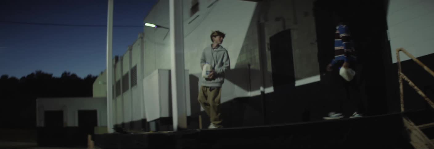 Two boys climbing the stairs in an outdoor area and throwing a gallon on the ground