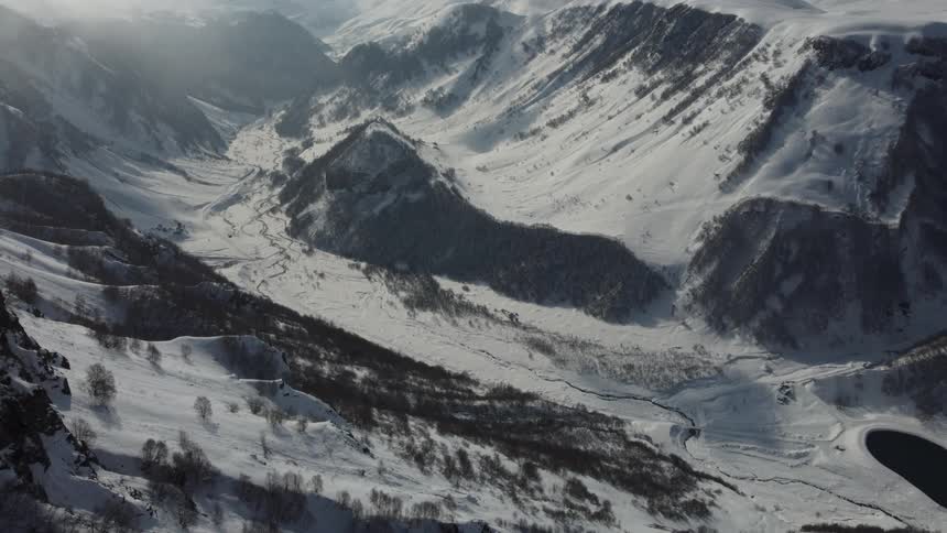 A snow covered valley stretches out below with a winding river snaking through the landscape