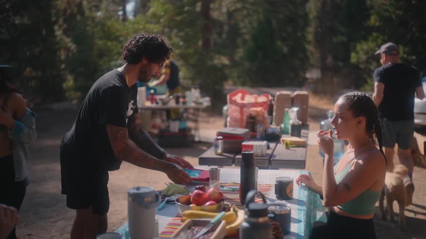 A table full of food and some people taking plates and serving themselves
