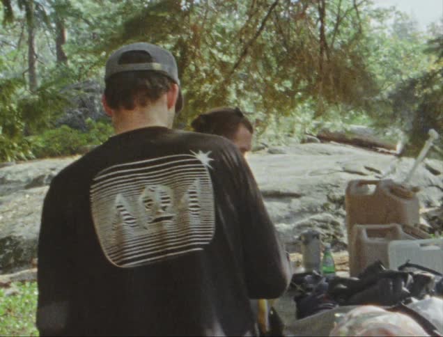 Four people in nature at an outdoor campsite during the day