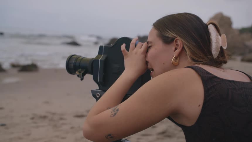 Woman using a professional camera while standing on the sand at the beach