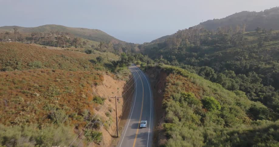 Aerial view of a car traveling on a highway surrounded by mountains