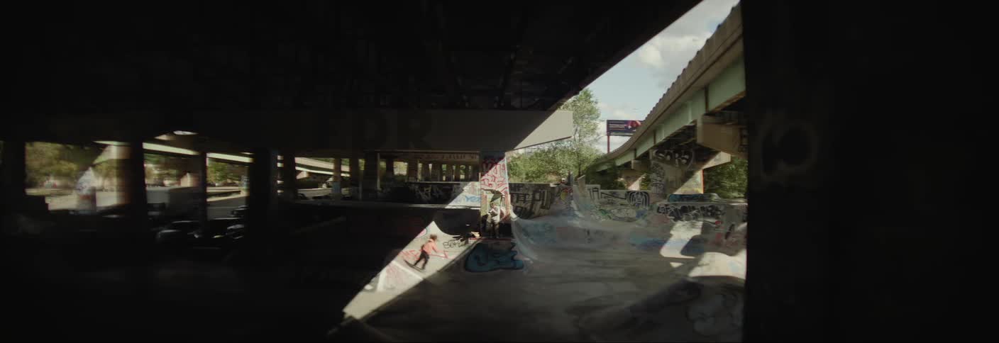 Person skateboarding on a large rink below an overpass
