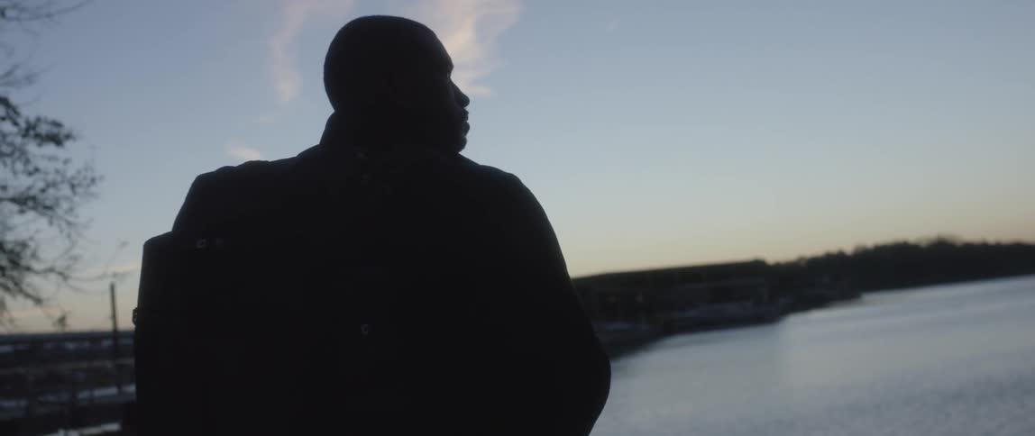 Man standing by the water looking out at the sky