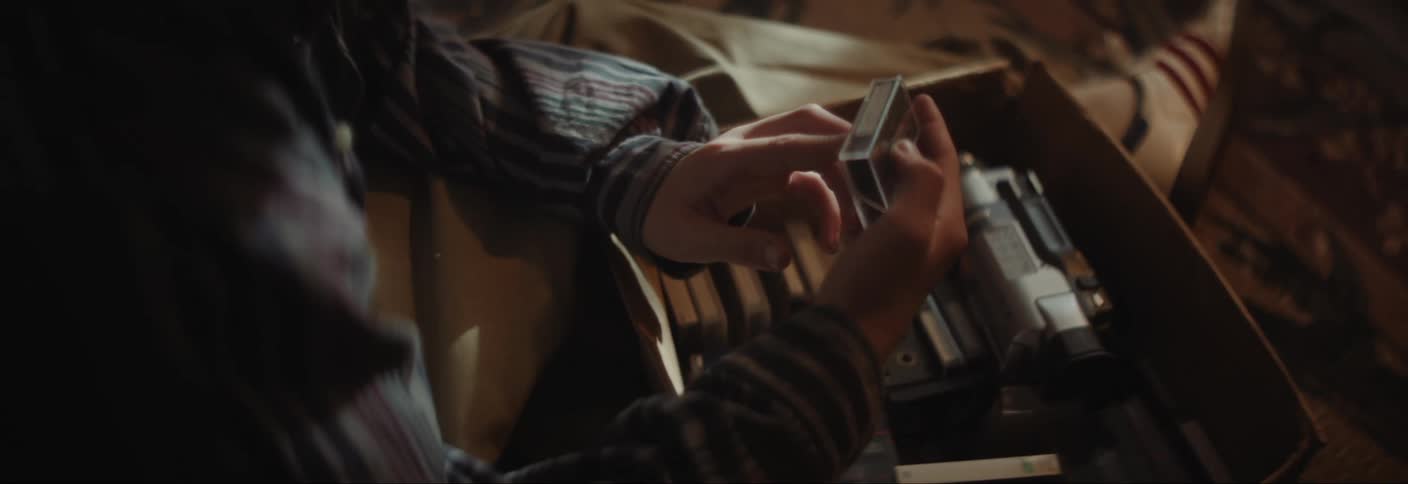 Pair of hands picking up a camera video tape inside a box
