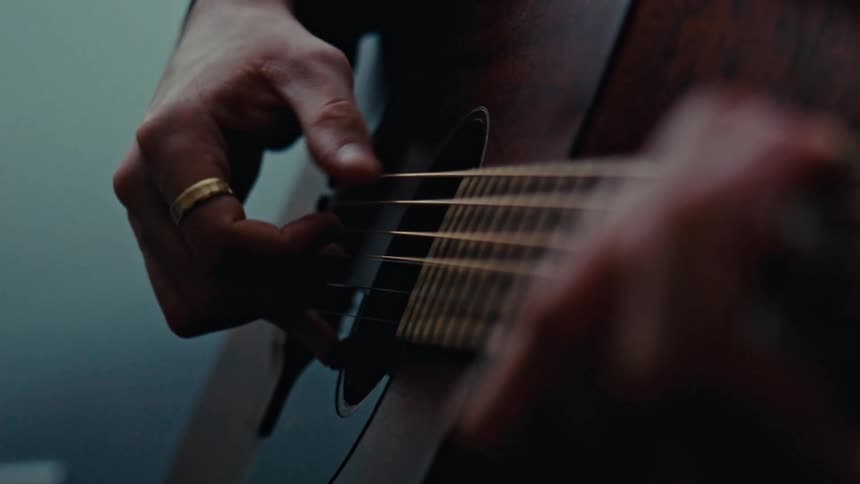 A man is strumming an acoustic guitar