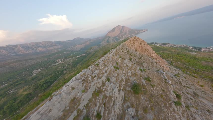 Aerial view of the ridge of a mountain range extending to a distant coastline