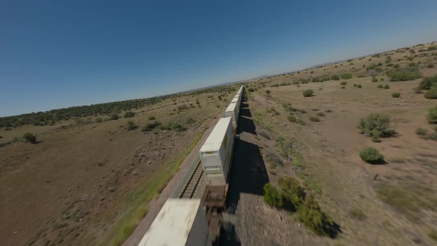 A long freight train snakes its way across a vast arid landscape