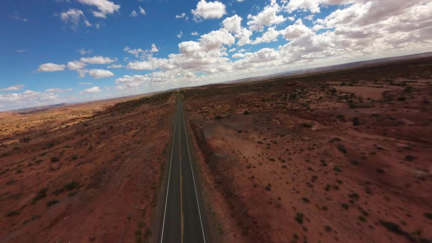 Aerial view of a paved highway surrounded by a desert environment with sparse vegetation