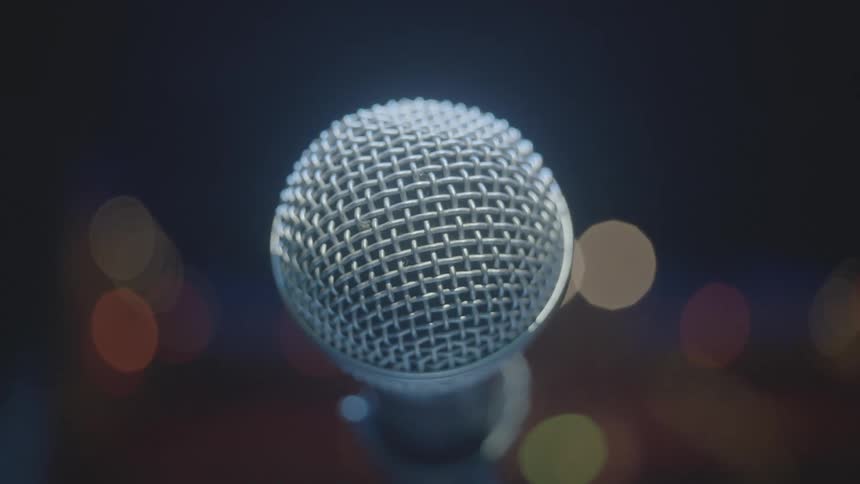 Close up of a microphone in an indoor space with abstract lights in the background