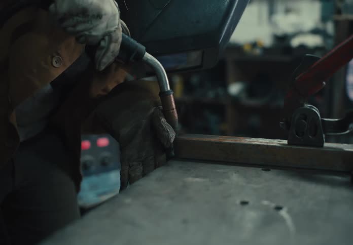 Welder with a protective helmet welding a metal