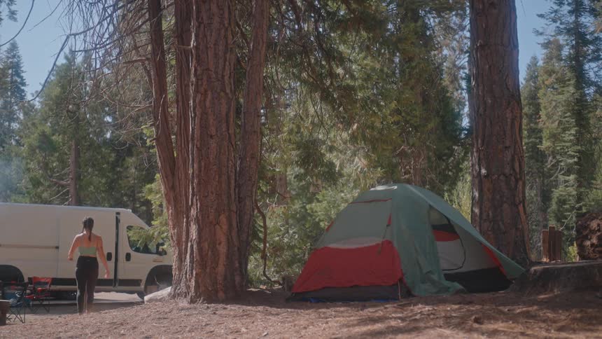 Woman leaving the tent and walking towards a van in a natural area
