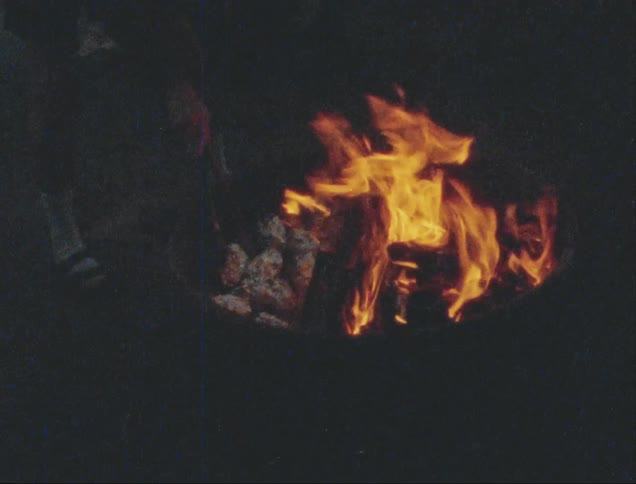 A person is stirring the flame of a campfire