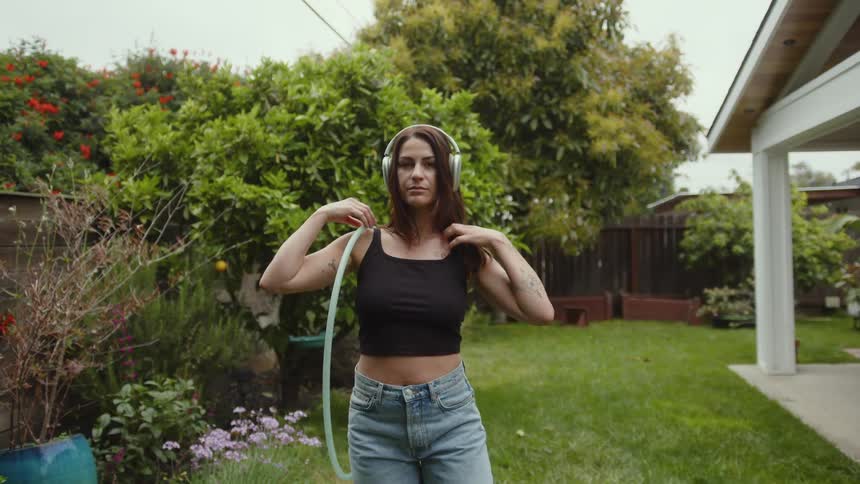 A woman holding a hula hoop smiles in the yard