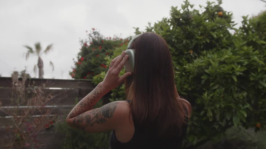 Woman from behind with long black hair putting on headphones