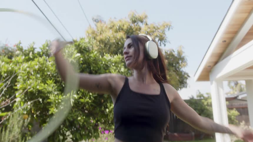 Woman dancing with headphones and a hula hoop in the backyard