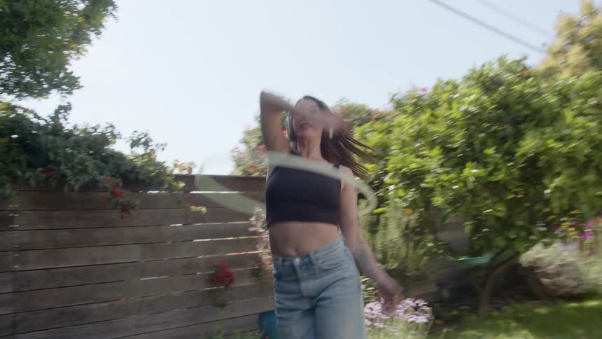 A woman is using a hula hoop while wearing headphones