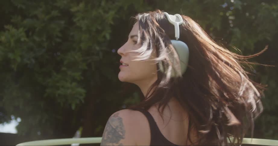 Woman dancing and spinning her body outdoors using headphones and a hula hoop