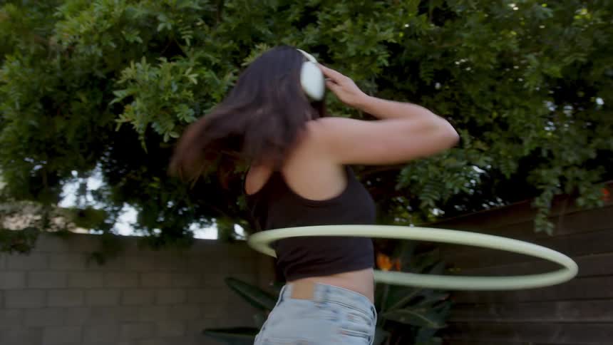 Cheerful woman dancing with a hula hoop and headphones