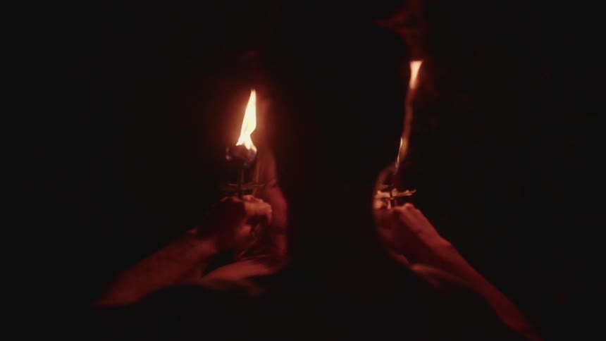 Two women in a ritual holding chalices with fire