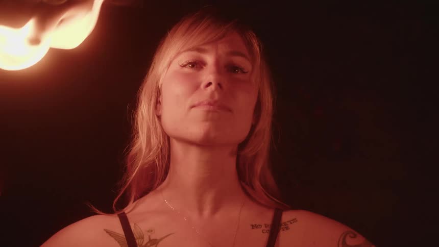 A woman waves around balls of fire