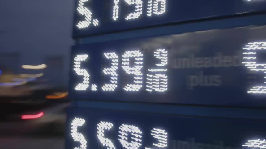 The gas station sign is lit and shows the prices