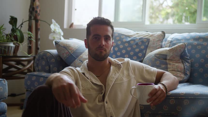 Man sitting on the floor in the living room holding a mug