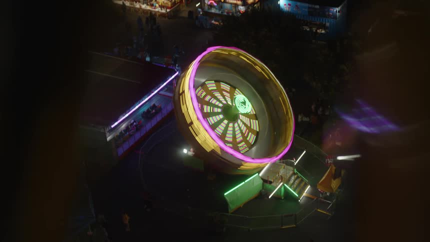 Top view of a spinning ride in operation at an amusement park at night