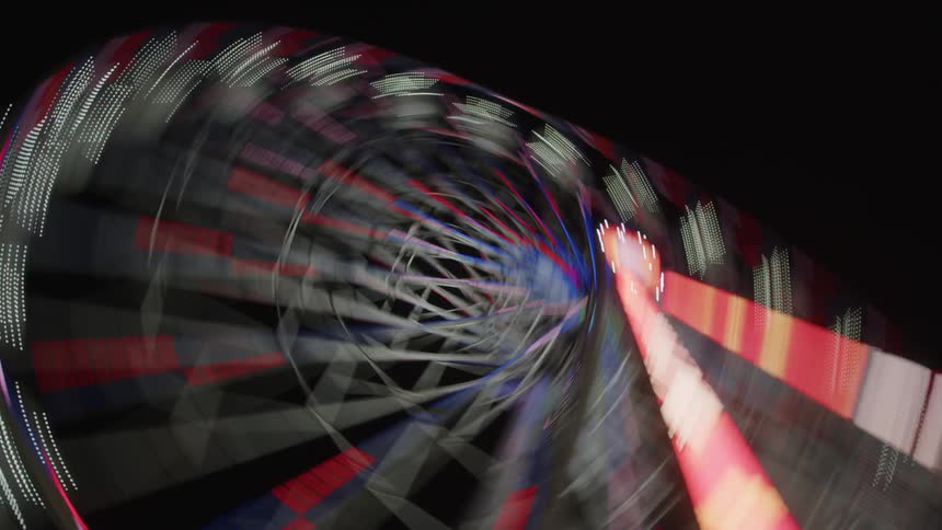 A dizzying abstract view of a spinning amusement park ride illuminated with vibrant lights