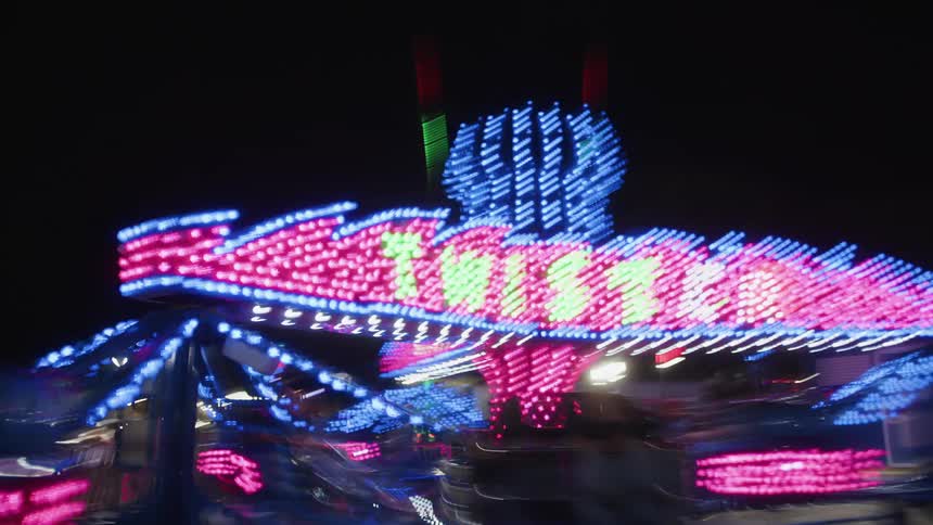 Neon light ride in operation at an amusement park at night