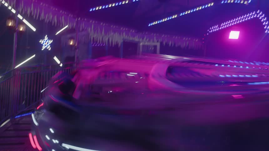 Environment filled with neon lights in shades of purple and blue an amusement park ride moves at high speed