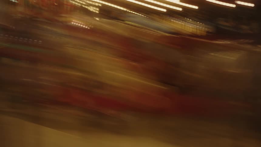 The footage shows a blurry carousel spinning at night illuminated by bright lights