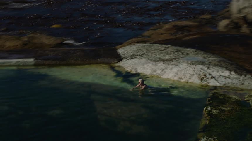 Person relaxing in a natural pool surrounded by the sea