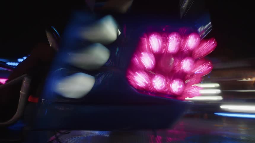 A carnival ride with flashing lights spins at night with the word twister illuminated in red and blue