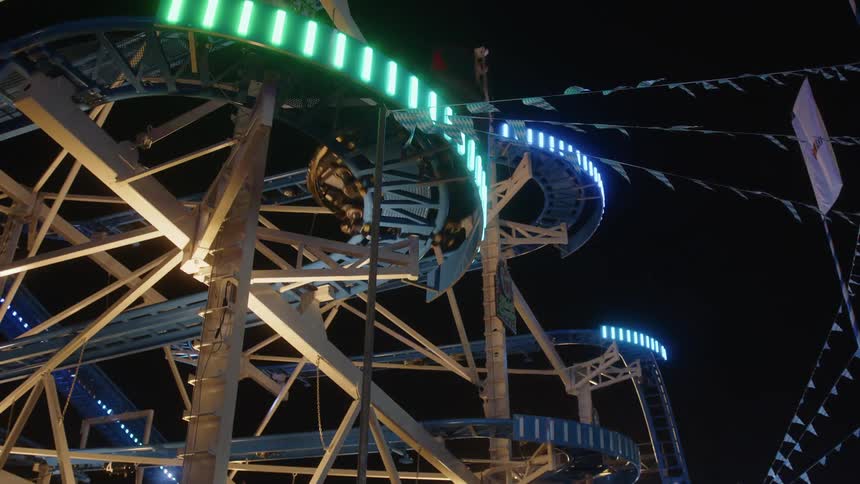 Upward view of a litup roller coaster at night in an amusement park