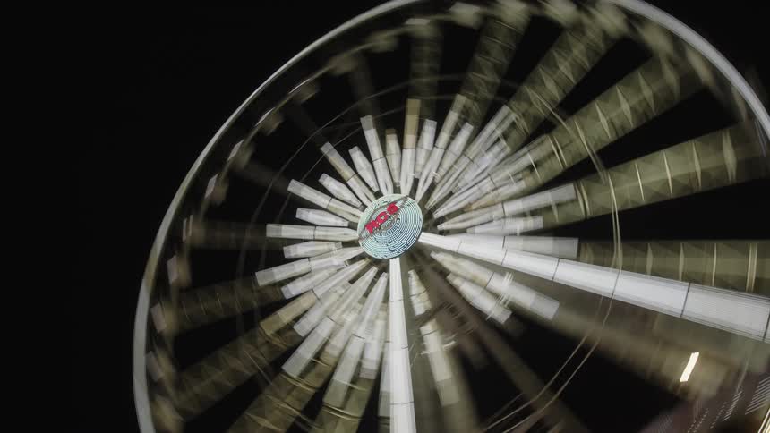 The large ferris wheel is spinning at night