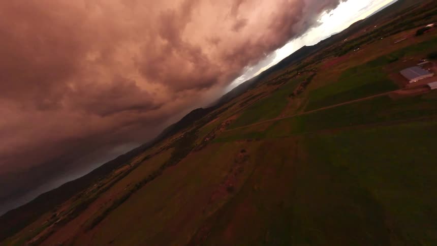Aerial panorama of a green field and a stormy sky