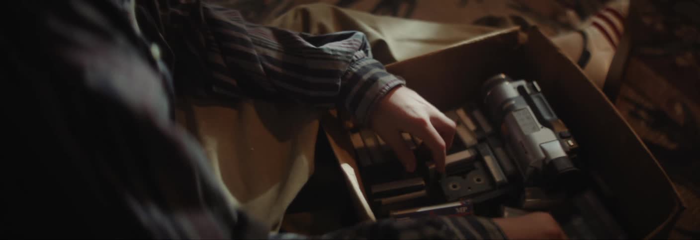 Pair of hands picking up old camera tapes from a box