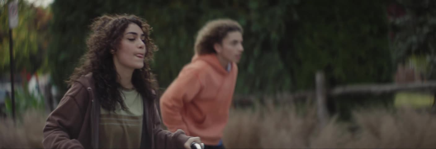 Two teenagers riding a bike and the other one riding a skateboard