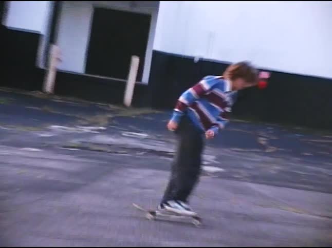 Curlyhaired teenager botching a skateboard trick