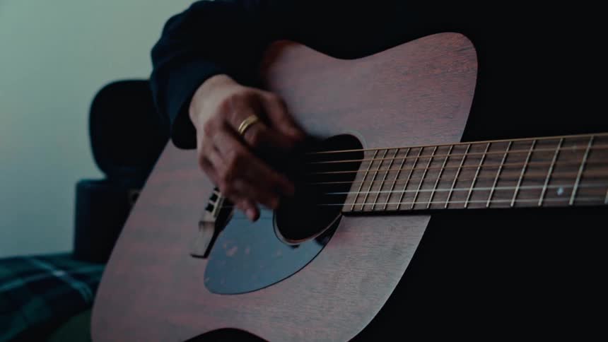 A man is nodding his head while playing the guitar
