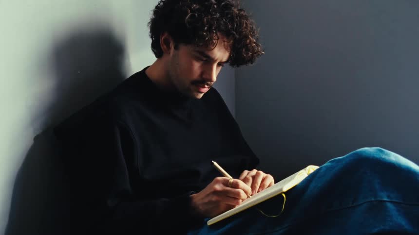 Man sitting on the floor writing in a book