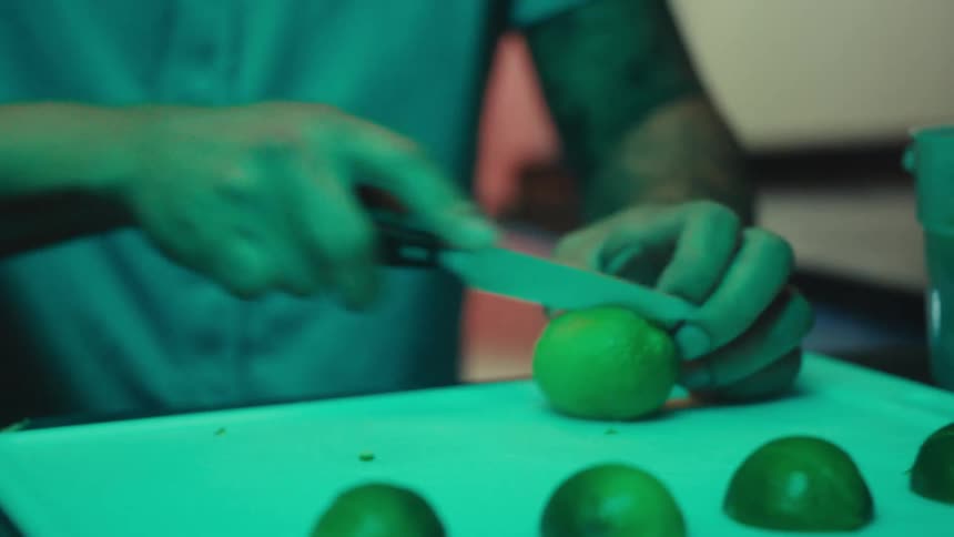 A man is slicing up limes on a cutting board