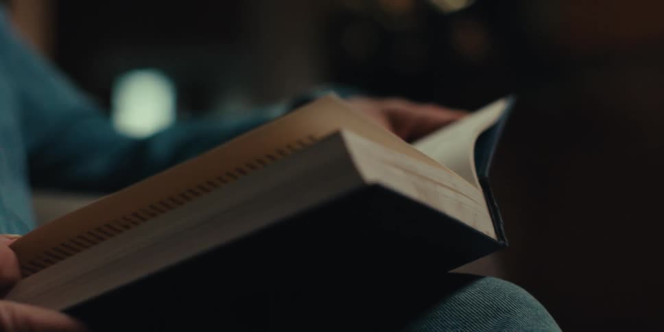 Elderly man focuses on the book he is reading while sitting at home