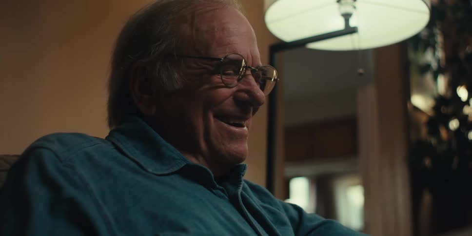 Elderly man sitting at home smiles happily while reading