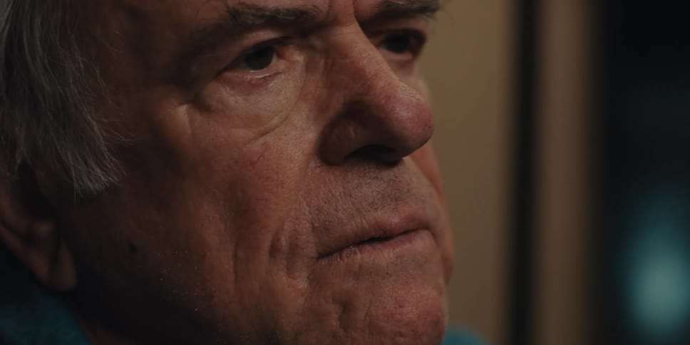 An elderly man looks concerned as he takes off his glasses
