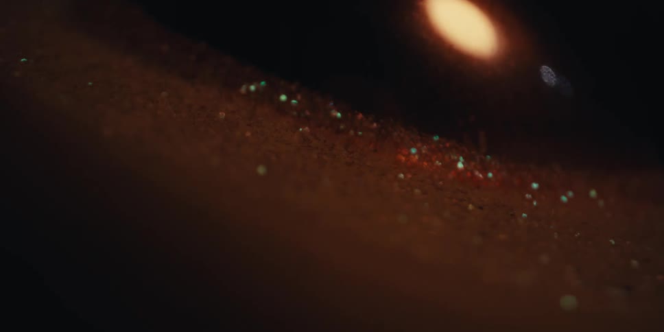 A dim spotlight shines on a spherical surface surrounded by glitter
