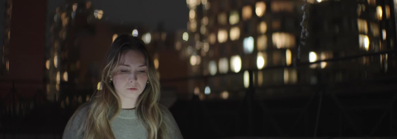 Woman sitting outdoors at night and turning on a laptop
