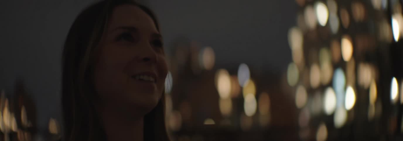 Closeup of a woman walking in a city at night with lights illuminating the buildings