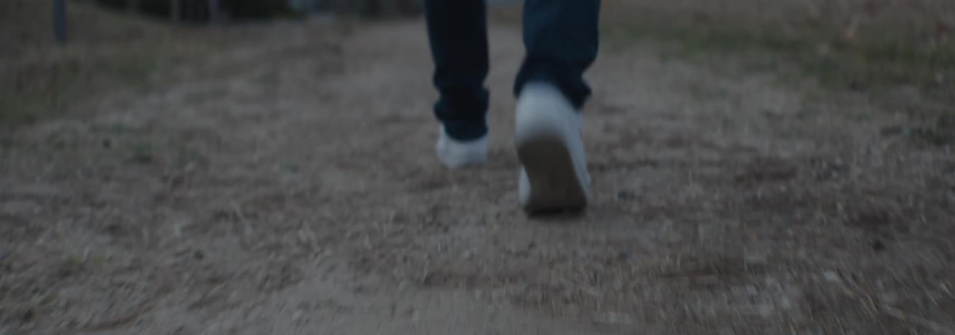 Legs of a person walking on a grassy path